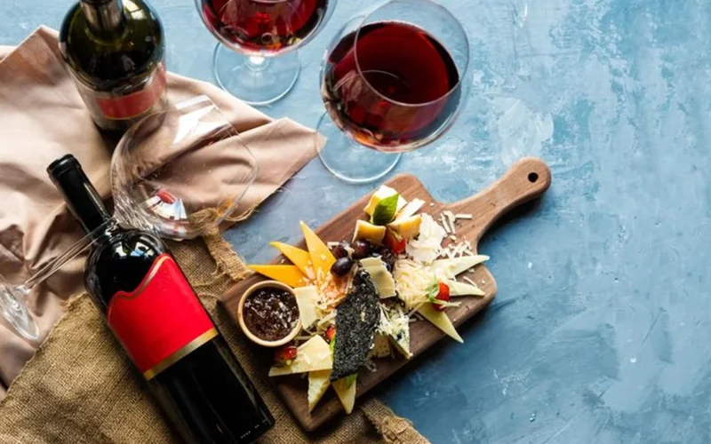 Overhead view of red wine and a mushroom provolone cheesesteak on a rustic table.