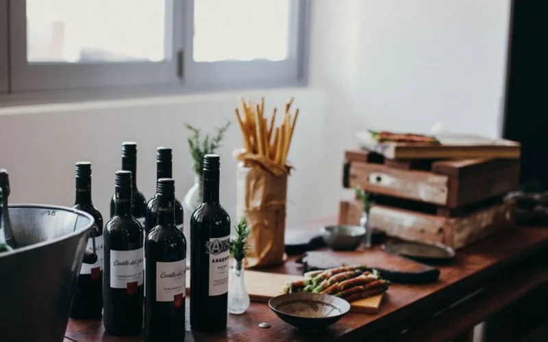 A red wine bottle and a white wine bottle resting on a dark wooden table.
