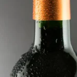 Macro close-up of water droplets on a chilled glass wine bottle surface.